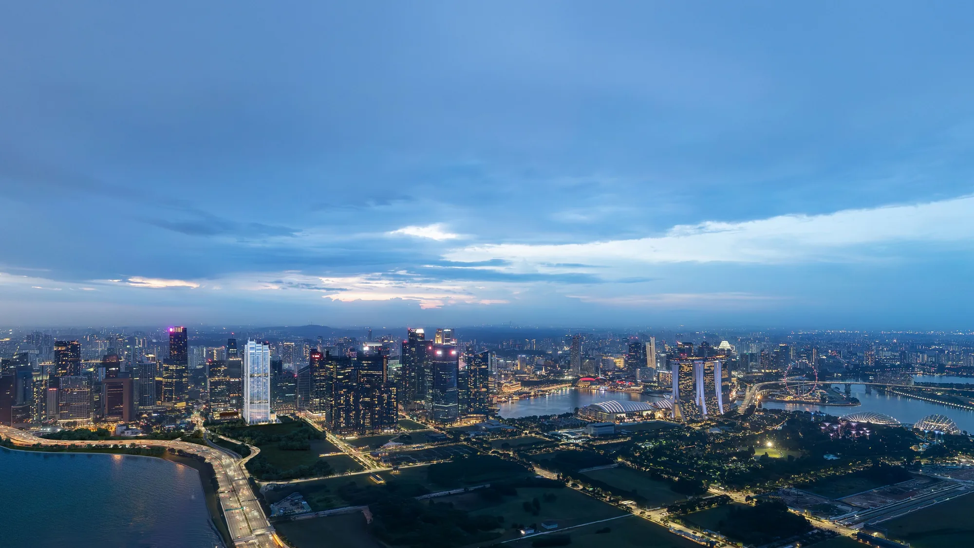 W Residences Marina View, artist&rsquo;s impression: an aerial panorama at blue hour, the white tower standing out in the skyline between the city and Marina Bay